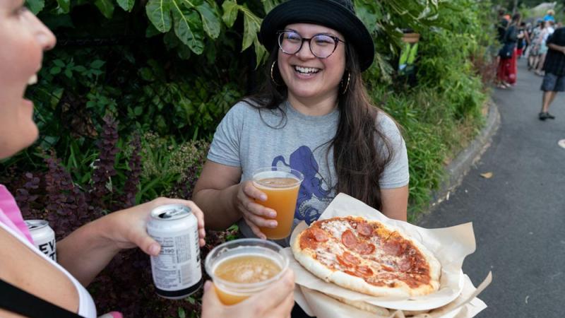 young adult visitors laughing with pizza and beer